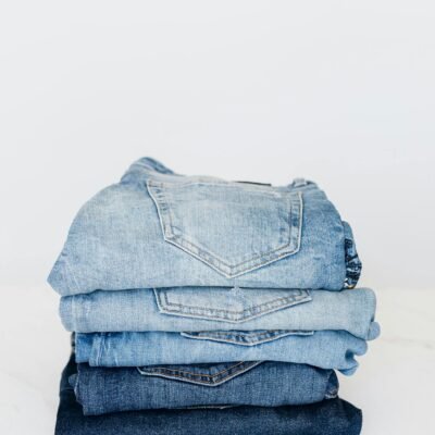 Pile of denim pants of different shades of blue placed on white shelf