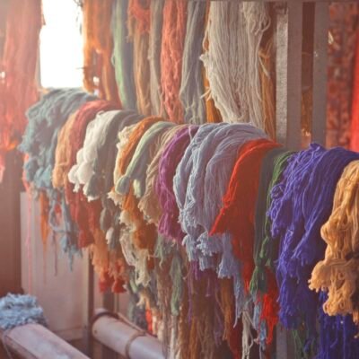 Skeins of multicolored threads for needlework hanging on wooden rack in light workroom